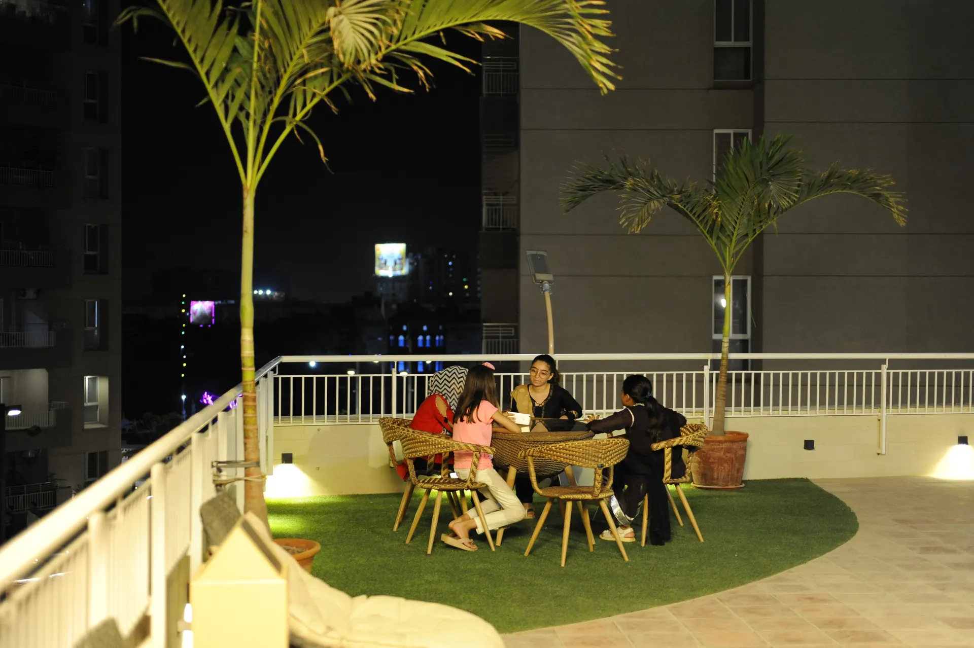 The rooftop at Lakhani Presidency after dark, a table laid under the palms.